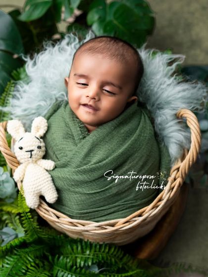 A duplicate of image 221, a peaceful, smiling newborn in a green wrap.