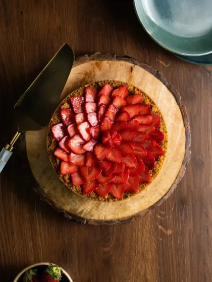 An overhead shot of our Strawberry Biscoff Cheesecake on a rustic wooden board. A simple, beautiful cake can make any table setting look special.