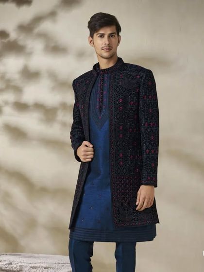 A deep blue Indo-Western outfit paired with a navy blue kurta. The jacket features intricate, tonal embroidery, creating a look of understated and sophisticated luxury.