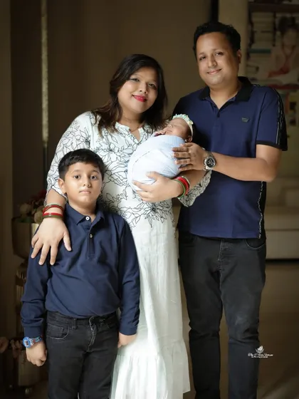 A classic standing family pose from a lifestyle session. The parents and older son stand together, with the mother holding the newborn, creating a perfect first family portrait of four.