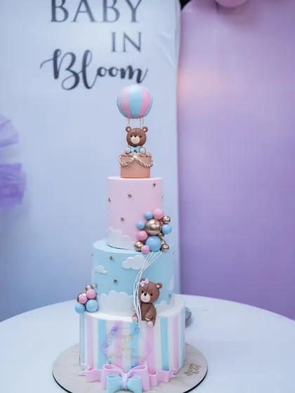 The stunning, multi-tiered cake for the baby shower. Adorned with cute teddy bears and a hot air balloon, it's a centerpiece that is almost too beautiful to eat.