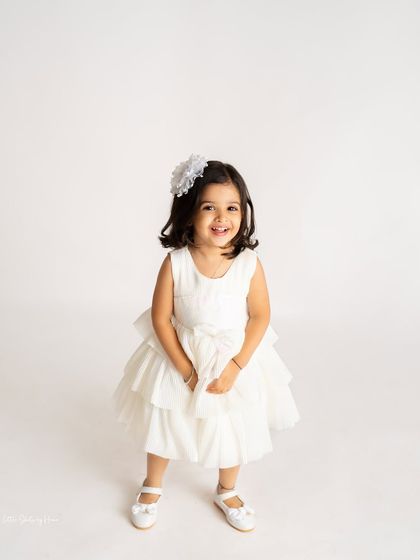 A beautiful solo portrait of the birthday girl. Her bright smile and pretty white dress make this a perfect shot to remember her turning three.