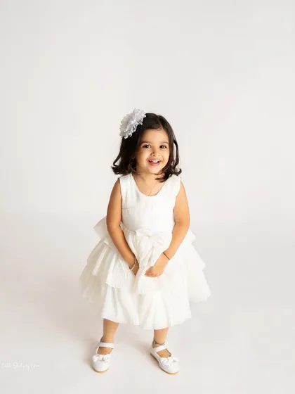 A beautiful solo portrait of the birthday girl. Her bright smile and pretty white dress make this a perfect shot to remember her turning three.