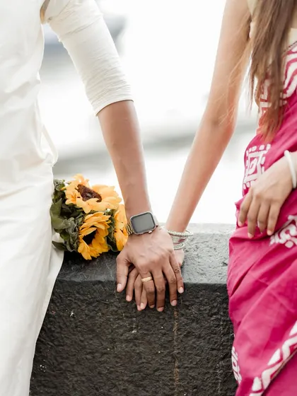 A close-up detail shot of the couple's hands, showing the engagement ring and traditional bangles. This focuses on the small, meaningful details of their union.