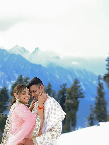 A close-up, intimate portrait of the couple against a backdrop of snow-capped mountains. This pre-wedding photo captures a tender moment in a grand, scenic location.