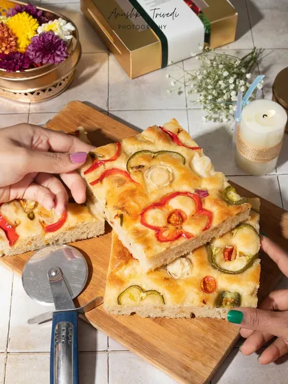 Hands sharing a slice of freshly baked focaccia bread. This image evokes a sense of community and sharing, making the food feel warm and comforting.