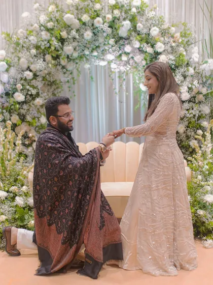 The moment of the proposal during the engagement ceremony. The groom is on one knee, and the bride's reaction is beautifully captured.