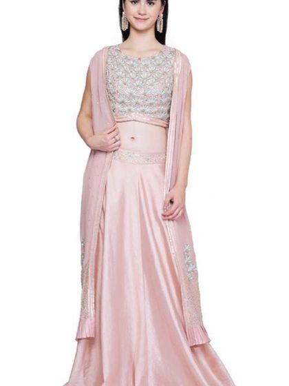 This elegant light pink lehenga set comes with a heavily embroidered sleeveless blouse and a matching embroidered capelet. The satin skirt adds a touch of luxury, making it perfect for a reception or engagement.