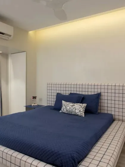 The son's blue room in the Mulund project. Designed for a tall teenager, it features a massive platform bed with a checked fabric frame and a clean, minimal aesthetic.