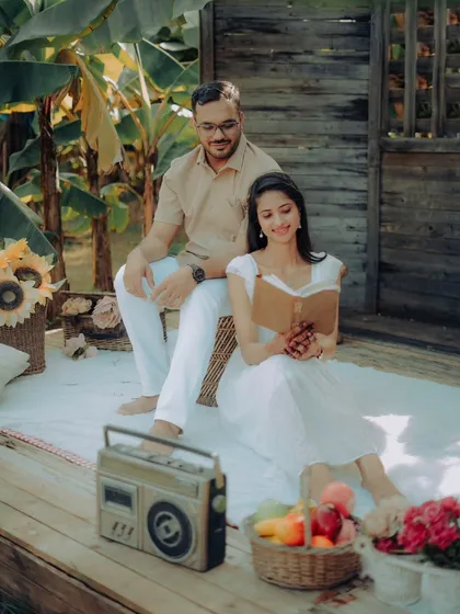 A charming picnic-themed pre-wedding shoot. Nikhil and Anisha relax with a book, a retro radio, and a basket of fruit, creating a sweet and nostalgic scene.