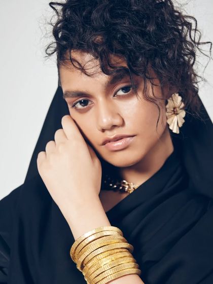 This pose highlights the beautiful combination of soft, natural makeup and bold gold accessories. The focus remains on the model's expressive eyes and flawless skin, a signature of my work.