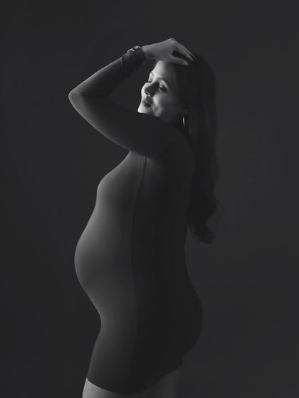 A classic black and white profile shot, beautifully capturing the silhouette and form of the expecting mother.
