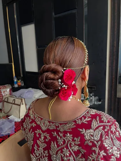 I love creating classic bridal buns that are both secure and beautiful. This intricate twisted updo is accented with vibrant red roses and delicate baby's breath, making it a timeless choice for the main wedding ceremony.