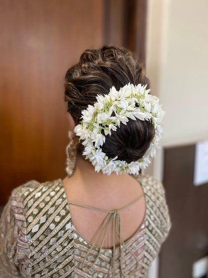 A classic gajra bun using fragrant jasmine flowers. This traditional South Indian hairstyle is a favorite for its elegance and beautiful aroma, making any bride feel special.