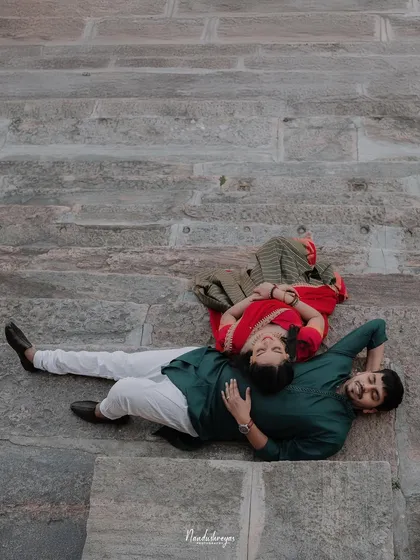 A relaxed, unconventional pose with the couple lying on the stone steps of a temple, seen from above.