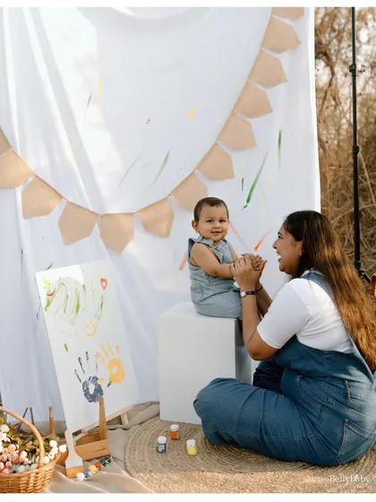 An outdoor painting session is a creative way to capture your family's playful side. Here, a mother and her baby share a laugh while creating their first masterpiece together.