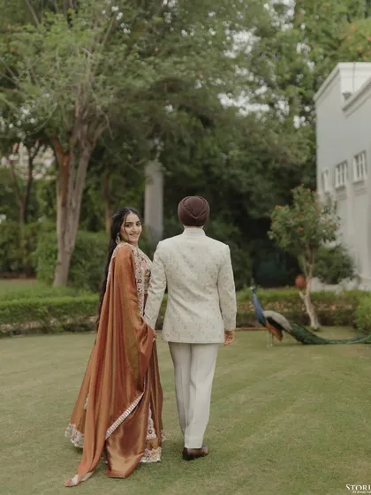 The couple walking away into a garden, with the bride looking back at the camera. This shot feels like a scene from a movie, complete with a peacock in the background.