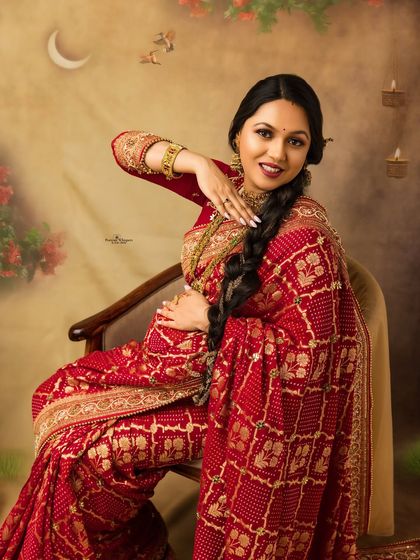 A playful and elegant seated portrait of a mother-to-be. Her beautiful red bandhani saree and traditional jewelry shine in this festive Karva Chauth themed shoot.