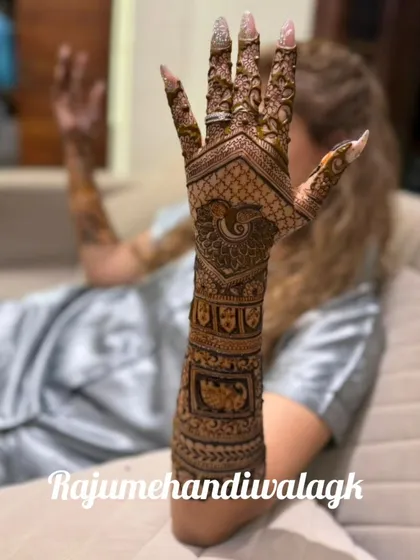 A relaxed pose showing the bride's full arm mehendi, featuring peacocks and traditional patterns.