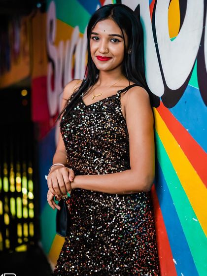 A guest in a sparkly black dress, posing by the colorful wall.