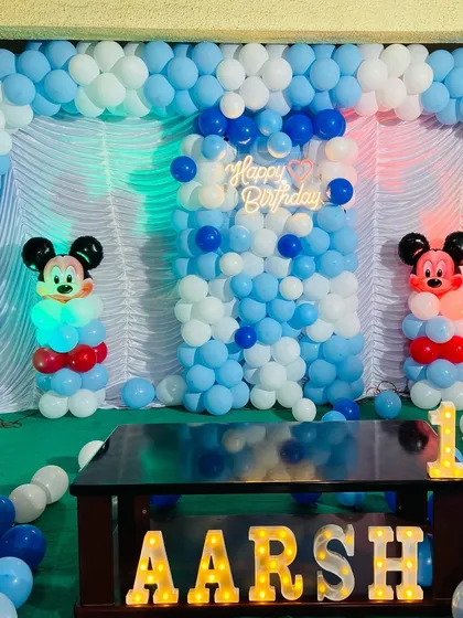 A close-up of the Mickey Mouse themed birthday stage for 'Aarsh', showing the balloon wall and character details.