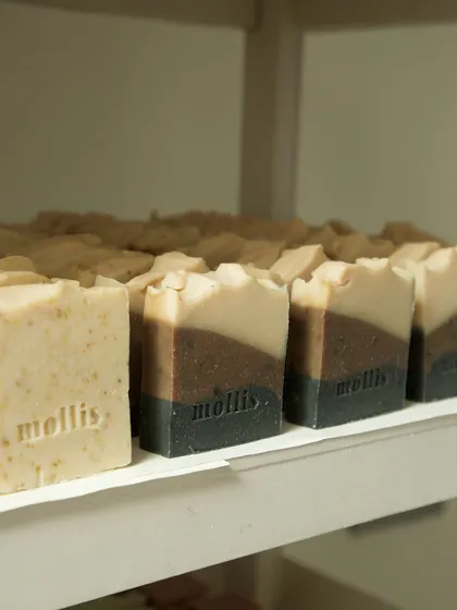 A row of freshly stamped soaps, including a gentle exfoliating bar and a layered design.