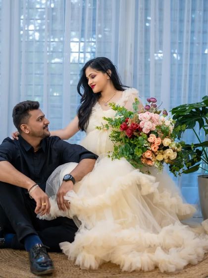A romantic studio portrait of a couple with a beautiful bouquet of flowers. The soft, creamy tones of the gown and the background create a dreamy feel.