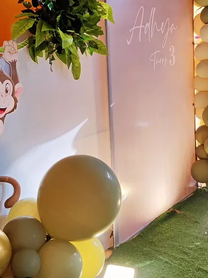 A detailed shot of a monkey-themed party, showing a cute monkey cutout swinging from a vine against an orange wall.