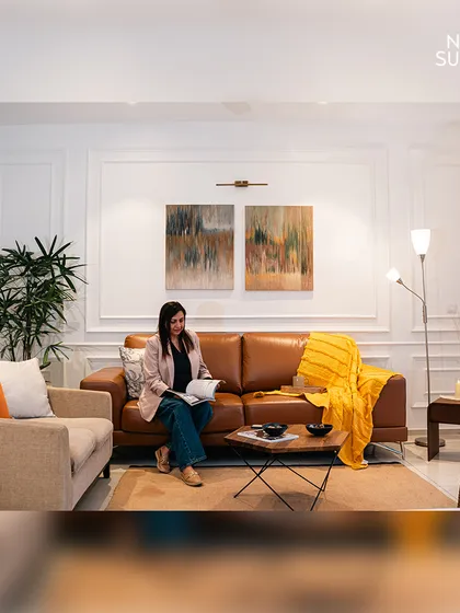 We believe living spaces should be both elegant and comfortable. Here, classic wall mouldings and warm lighting create a sophisticated backdrop for the rich tan leather sofa and curated artwork, resulting in an inviting atmosphere for relaxation and socializing.