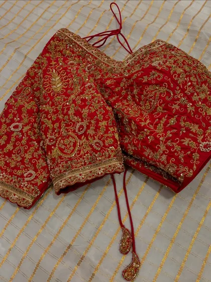 A classic red bridal blouse is timeless for a reason. This piece is covered in heavy, intricate zardosi and thread work, designed to be the perfect regal complement to a wedding saree.