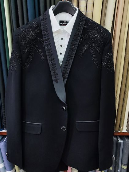 The finished masterpiece. A custom black wedding suit with delicate, leaf pattern hand embroidery, hanging in the studio before being delivered to the client.