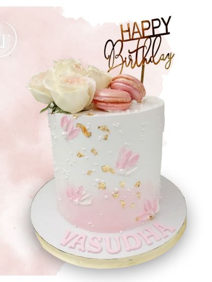 A lovely pink and white birthday cake for Vasudha, topped with fresh roses and macarons.