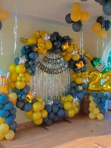 A 22nd birthday ring decoration in yellow and black, with a champagne bottle and beer mug foil balloon for a fun touch.