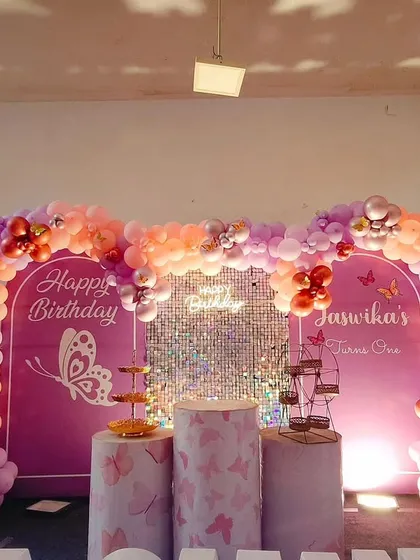 A lovely butterfly theme with a double-arch backdrop. The setup uses shades of purple, pink, and orange balloons, a central shimmer panel, and butterfly graphics for a beautiful and cohesive look.