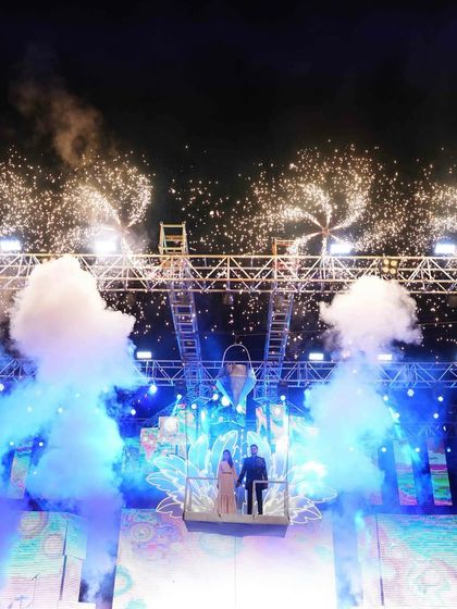 Another angle of the couple's aerial entry, showcasing the massive truss structure and the dramatic effect of the smoke and fireworks from below.