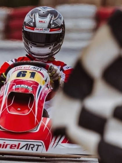 Driver Abhay in his number 61 kart crossing the finish line, marked by the checkered flag, to secure another victory for the team.