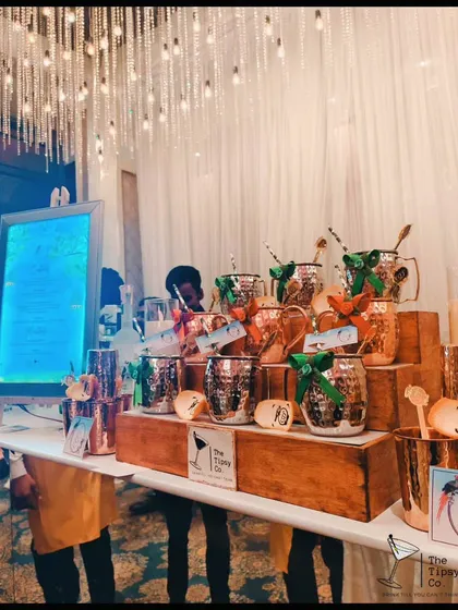 A beautiful display of Moscow Mule mugs, each adorned with a festive ribbon. This setup is perfect for a winter wedding or holiday party, adding a touch of rustic elegance.