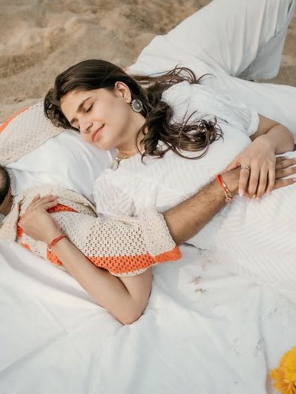 A peaceful moment of rest during their beach picnic. The couple lies together on the blanket, capturing a feeling of complete comfort and trust.