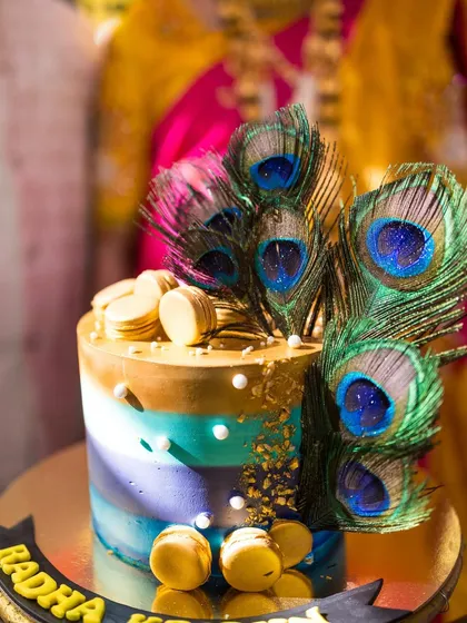 A stunning peacock-themed cake, adorned with real peacock feathers and golden accents. This was the centerpiece of a beautiful Radha-Krishna themed baby shower.