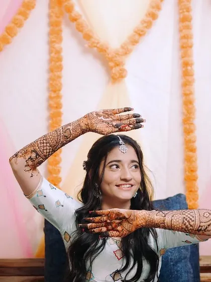 The bride playfully showing off her intricate mehndi design. This shot captures her happy and excited mood during the ceremony.