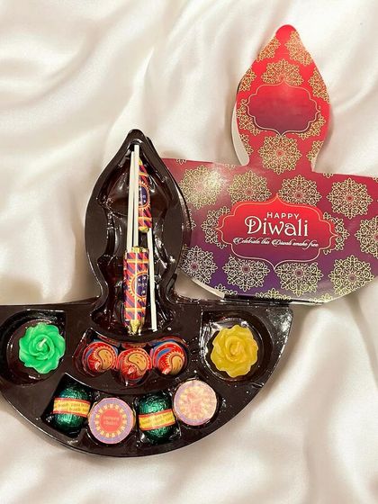 A creative Diwali gift box shaped like a traditional diya. Inside, it holds a delightful assortment of chocolates shaped like firecrackers and diyas.