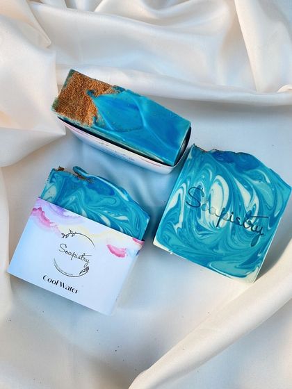The "Cool Water" soap bar, with its ocean-blue swirls and a layer of exfoliating sand. It has a fresh, masculine scent.