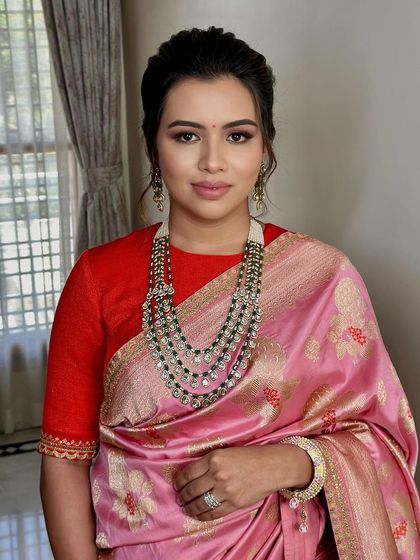 A portrait showing the elegant pairing of the pink saree with a contrasting red blouse.