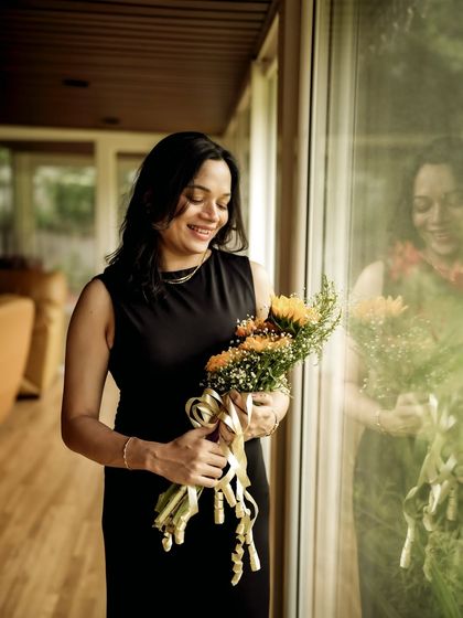 A happy indoor portrait. The mom-to-be holds a bouquet of sunflowers, her smile and the flowers bringing warmth and light to the scene.