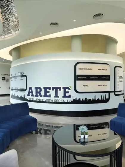 The reception and lounge area of a high-end corporate center, featuring a central, circular information hub with integrated graphics. The curved blue sofas and plush armchairs create a comfortable and sophisticated waiting area for visitors.