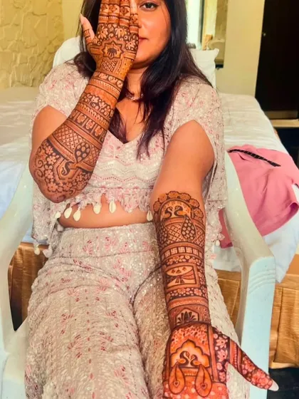 A happy client showing her engagement mehndi with the initials 'SS' on both palms.