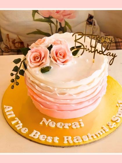 A simple and sweet cake with ombre pink ruffles and a topper of fresh roses.