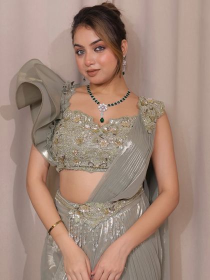 Another angle of the sage green saree, highlighting the dramatic ruffle sleeve. This contemporary twist adds a touch of high fashion to the traditional drape.