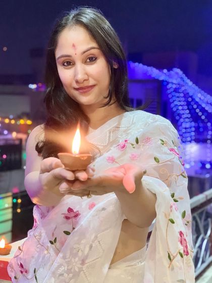 Holding a diya during Diwali celebrations. I'm wearing a delicate white organza saree with pink floral embroidery, which felt perfect for the festival of lights.