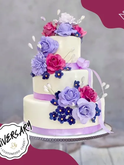 A magnificent three-tier anniversary cake with a cascade of purple and pink sugar flowers. This grand and elegant creation is perfect for a milestone celebration.